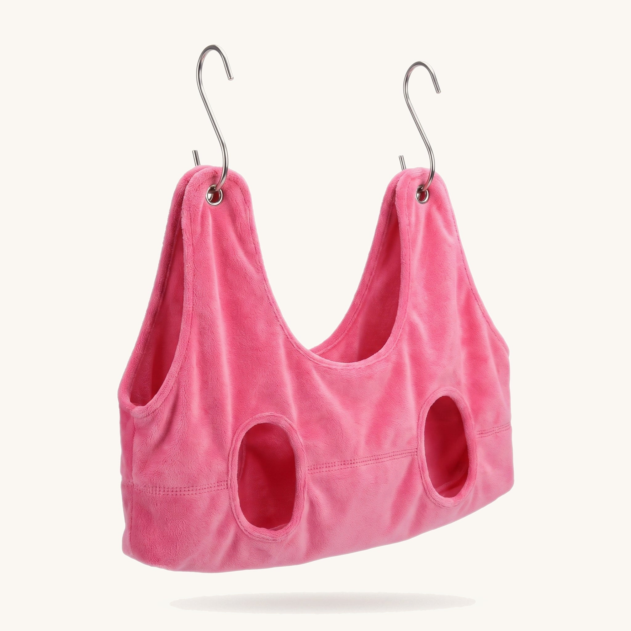 Pink dog grooming sling hammock with metal hooks on a warm off-white background